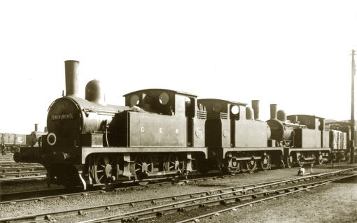 E22 no.155 heads a lineup including T18 no. 318 and an unidentified M15 built after 1905. Both the E22 and T18 have been rebuilt (no.155 in 1905 and no.318 in 1904) - with 160psi telescopic boilers and the clack valves seated forward. The Nacallen blaspipe operating lever is prominent on the smokebox,  and the Roscoe lubricator has been removed. No.155 was a regular on the Blackwall line for many years and is running as a 2-4-0T.  The locos are all pretty grimy and there's considerable heat distress to the E22s smokebox and chimney. Photograph ©Public Domain.